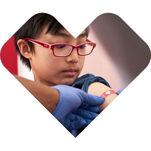 A child in red glasses receiving a bandage after a vaccine at MinuteClinic, in a heart-shaped frame